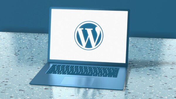 A blue laptop displaying the WordPress logo on a speckled blue surface