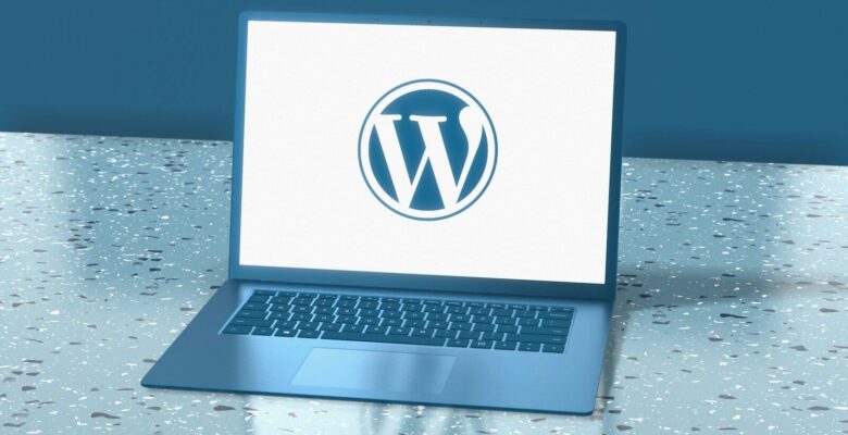 A blue laptop displaying the WordPress logo on a speckled blue surface