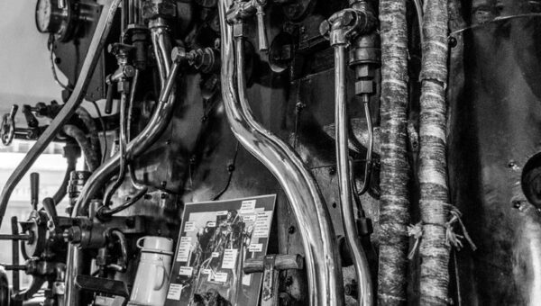 Black and white photo showing intricate steam train controls and gauges.