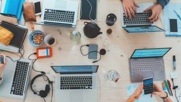 people sitting down near table with assorted laptop computers